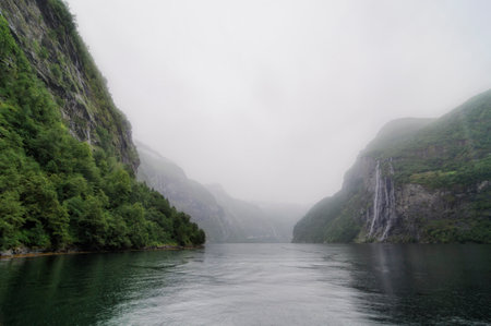 waterfalls falling in a fiord on a foggy day in norwayの写真素材