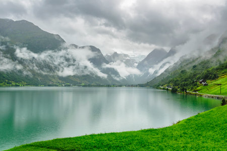 blue and turquoise water in a fiord in norway with a lot of clouds and fogの写真素材