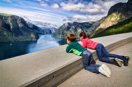 two children viewing the summer landscape in a viewpoint above a fiord in Norway. this viewpoint is located high in a Mountain next to a fiord in Aurdal in the fiord of the dreamsの写真素材
