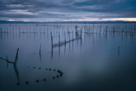 sunset in the Albufera lake in Valencia, Spain with fishing traps on the water and snow on the mountains in the backgroundの写真素材