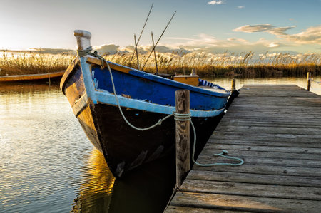 a fishing boat in the pier in the albufera lake in Valencia, Spain with golden light at sunsetの写真素材