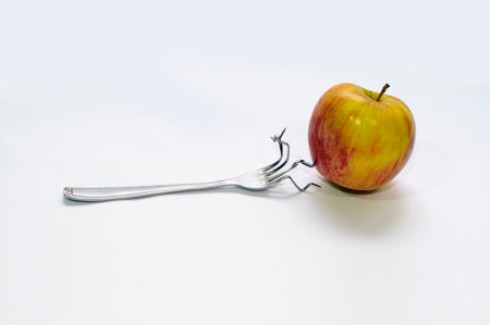 wrinkled fork trying to puncture a healthy and strong appleの写真素材