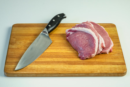 chopped pieces of pork on a wooden board next to the knifeの写真素材