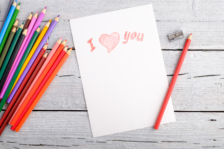 group different colored pencils on white paper on old wooden background closeup, postcard for Valentine's day, copy space for text, top viewの写真素材