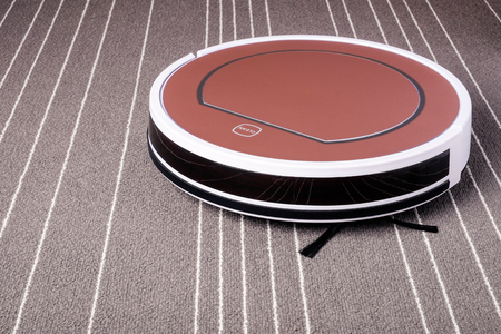 robotic vacuum cleaner on grey carpet with white stripes smart cleaning technologyの写真素材