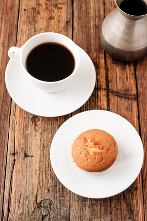 A Turkish coffee set with Cezve muffin and white cup, served on wooden tableの写真素材