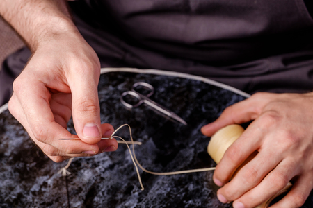 leather needle and waxed thread in men's hands, tools used by shoemakersの写真素材