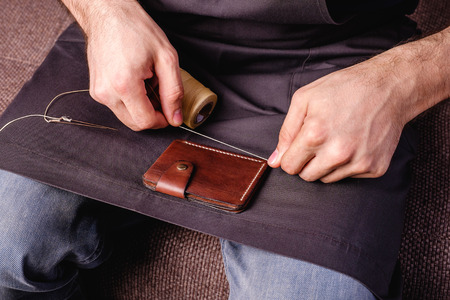 home made leather brown wallet small business, men's hands sewing