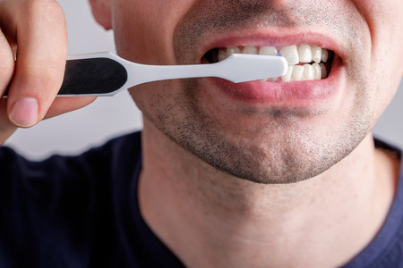 man cleaning teeth with plastic toothbrush closeupの写真素材