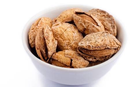 salted almonds in shell on white plate close up on white backgroundの写真素材