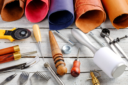 Leather craft tools and utensils on a white wooden backgroundの写真素材