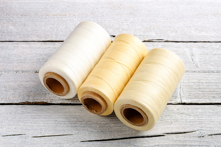 Colorful wax cord, leather thread reel on wooden background for leather crafting, wicker work and handcrafts.の写真素材