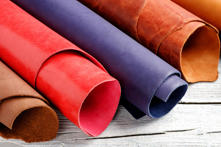 Brightly colored leather in rolls on the white wooden background. Leather craft.の写真素材