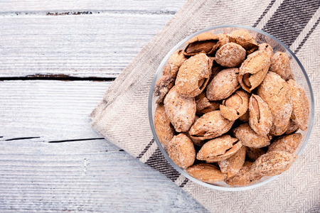almond on glass plate on light grey linen napkin on white wooden background, copy space for text, top view.の写真素材