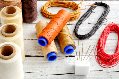 Colorful wax cord, leather thread reel on wooden background for leather crafting, wicker work and handcrafts.の写真素材