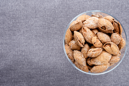 almond on glass plate on dark grey linen napkin background , copy space for text, top view.の写真素材