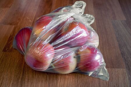 Apple fruit in plastic bag on wood tableの写真素材
