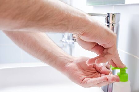 Washing hands with soap under running water in the bathroomの写真素材
