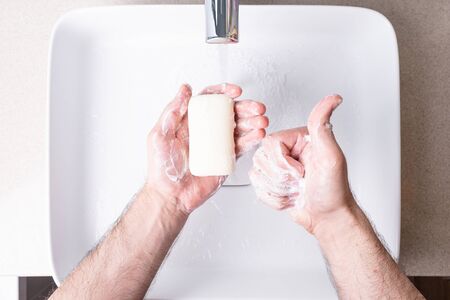 Washing hands with soap under running water in the bathroom
