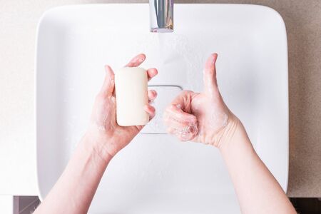 Washing hands with soap under running water in the bathroomの写真素材