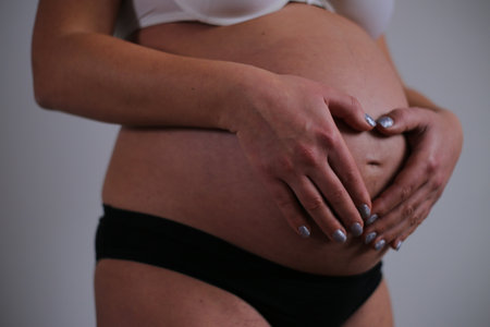 Pregnant woman touching her belly with hands, close-upの写真素材