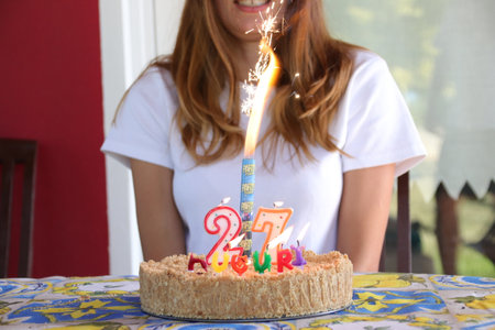 Girl smiling in front of birthday cake with burning candlesの写真素材