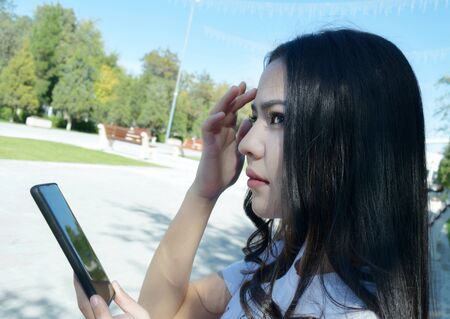 beautiful young girl with smartphone looking into the distanceの写真素材