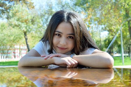 portrait of a young beautiful girl with long brown hair sitting at the tableの写真素材