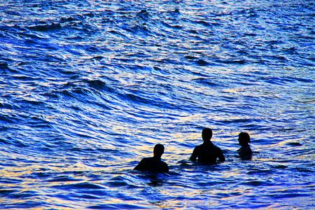 Swimmers / divers in the sea at dusk in the bay of Durdle Door on the Jurassic Coast, South Englandの写真素材