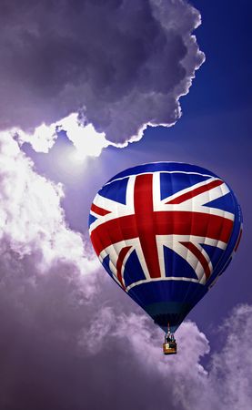 Colouful red white and blue hot air balloon rising in a cloudy skyの写真素材