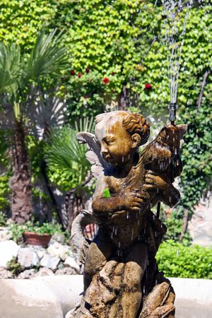Italian Eros water fountain in a gardenの写真素材