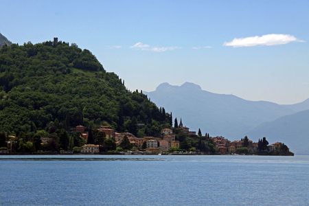 View of tree covered mountains and village at Lake Como in Italyの写真素材