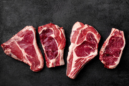 Meat raw steak lies on a black background. side view, copy space, top view