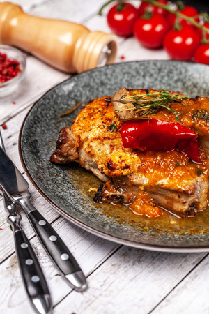 Mexican cuisine, pork or beef steak with a spicy sauce of salsa. with red pepper, marasm and titanium, cherry tomatoes, knife and fork.の写真素材