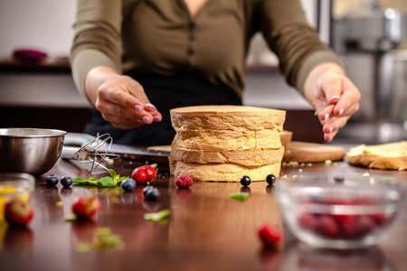 The pastry chef prepares a biscuit cake in the home kitchen or in a restaurant. The concept of the...