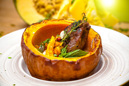 Dish on Halloween. Pumpkin soup in a pumpkin dish with meat, with thyme and cherry tomatoes. The concept of a beautiful dish in the restaurant. Copy space, selective focusの写真素材