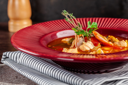 French cuisine concept. Classic French fish soup of seafood, shrimps, mussels, squid, potatoes, tomatoes. Beautiful serving dishes in the restaurant. copy spaceの写真素材