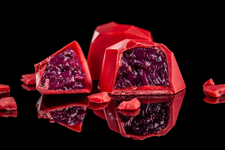 Chocolates red candy hearts isolated on black background with reflection. Valentines day romantic dessert composition, creative designer modern candies, sweets giftの写真素材