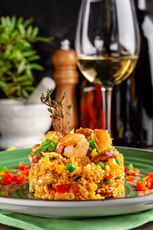 European Spanish cuisine. Paella with shrimps, chicken and coblas chorizo. White wine on the table. Closeup background image. Beautiful serving dishes in the restaurant. copy spaceの写真素材