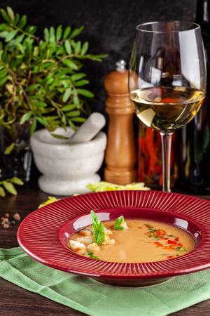 European Spanish cuisine. Summer tomato soup Gospacho with crackers, and vegetables. White wine on the table. Close-up background image. Beautiful serving dishes in the restaurant.の写真素材