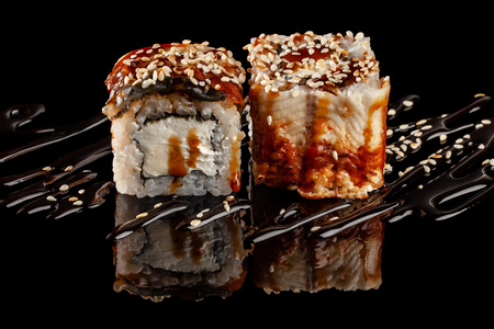 Concept of Asian cuisine. Two rolls of sushi with different fillings on a black background with the age for a Japanese menu for a cafe, restaurant, sushi bar.の写真素材