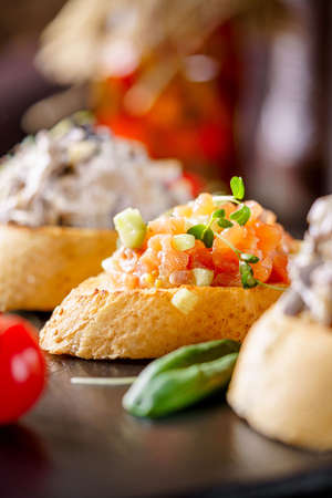 Italian Cuisine. Salmon baguette bruschetta, tomato and avocado. Serving food in a restaurant on...