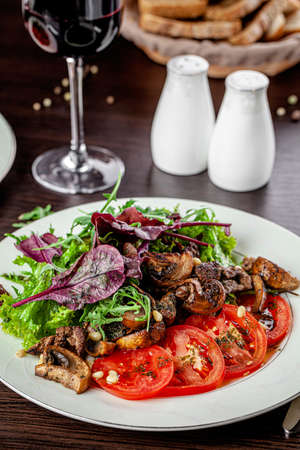 Mushroom and tomato salad dressed with pesto sauce and pine nuts. Serving food in a restaurant on a white plate.の写真素材