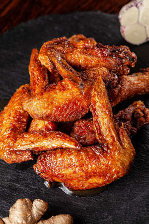 American cuisine. Fried chicken wings glazed in marinated with ginger and garlic on a black background. background image, copy space text.の写真素材