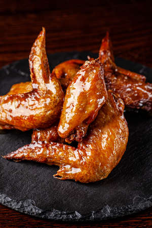 American cuisine. Fried chicken wings glazed in honey sauce on a black background. background image, copy space textの写真素材