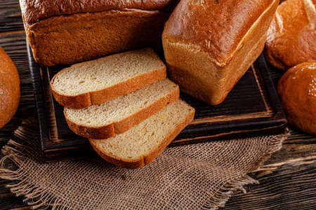 Assorted bread for catalan shooting. Long loaf, buns, baguette, pigtail, shaped. Bread on a wooden background. background image, copy space textの写真素材