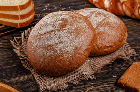 Assorted bread for catalan shooting. Long loaf, buns, baguette, pigtail, shaped. Bread on a wooden background.の写真素材