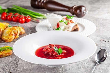 Modern Ukrainian cuisine in European style. Borsch soup with meat and sour cream. Beautiful serving dish in a restaurant in a white plate. background image, copy space textの写真素材