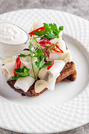 Ukrainian cuisine in the European style. Salted fat on black bread Snack for borscht soup. Beautiful serving dish in a restaurant on a white plate. background image copy space textの写真素材