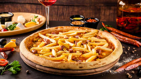 Italian Cuisine. Thin Oktoberfest pizza with french fries, hunting sausages and corn. Background image. copy spaceの写真素材